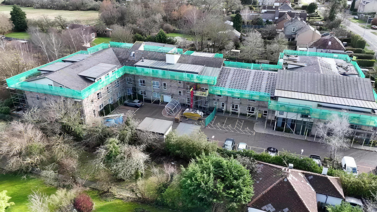 Residential block under green scaffold netting, filmed from the air